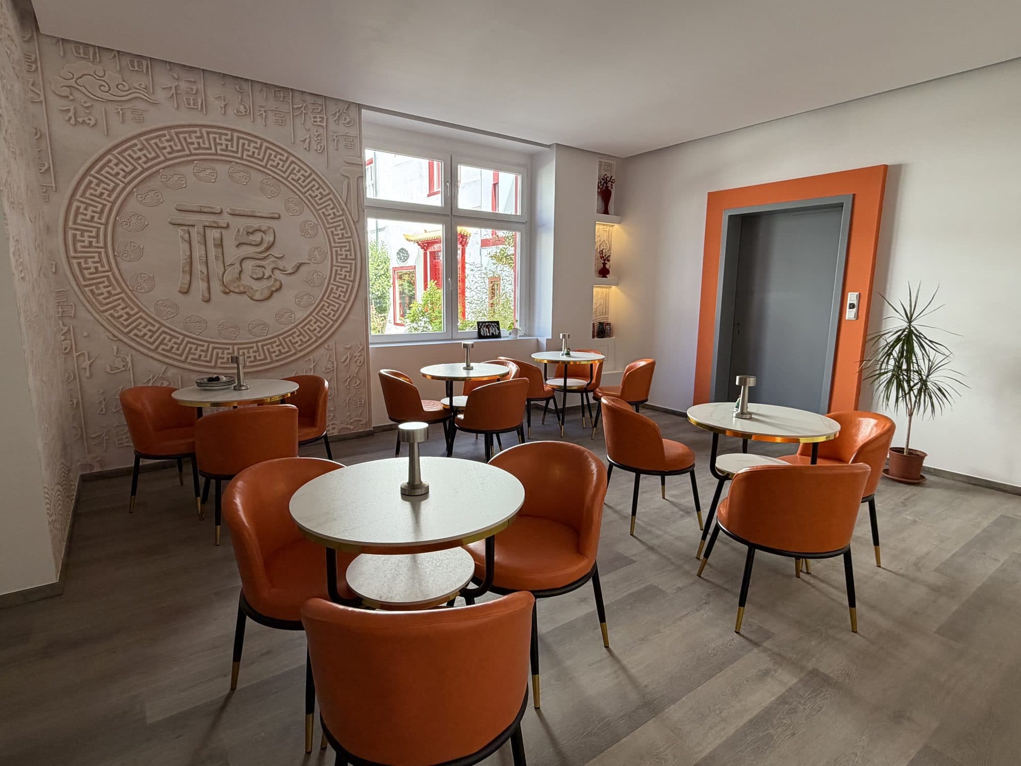 Frühstücksraum mit chinesischem Schriftzeichen an der Wand und Fahrstuhl im Hintergrund