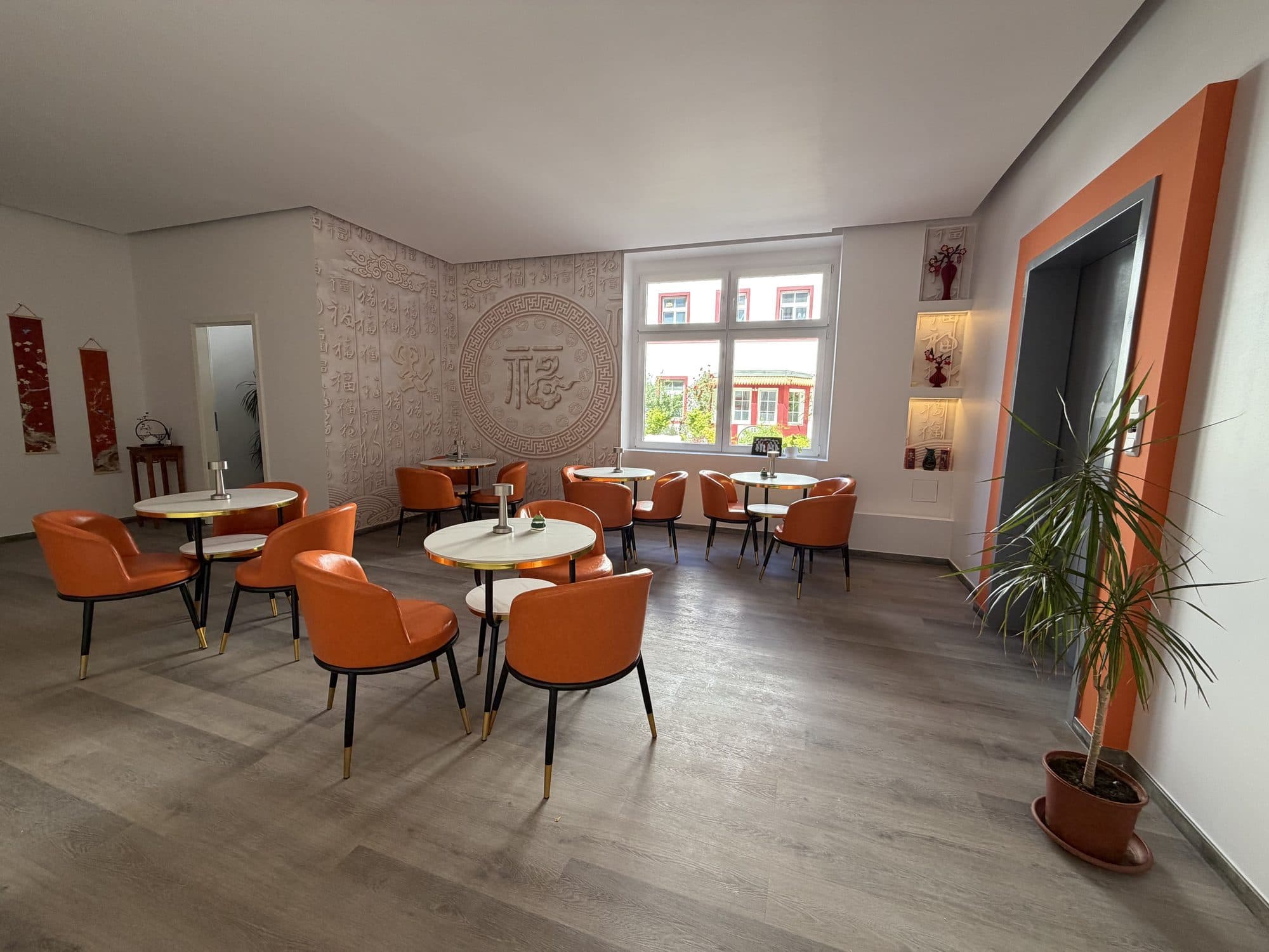 Frühstücksraum mit runden Tischen und orangefarbenen Sesseln