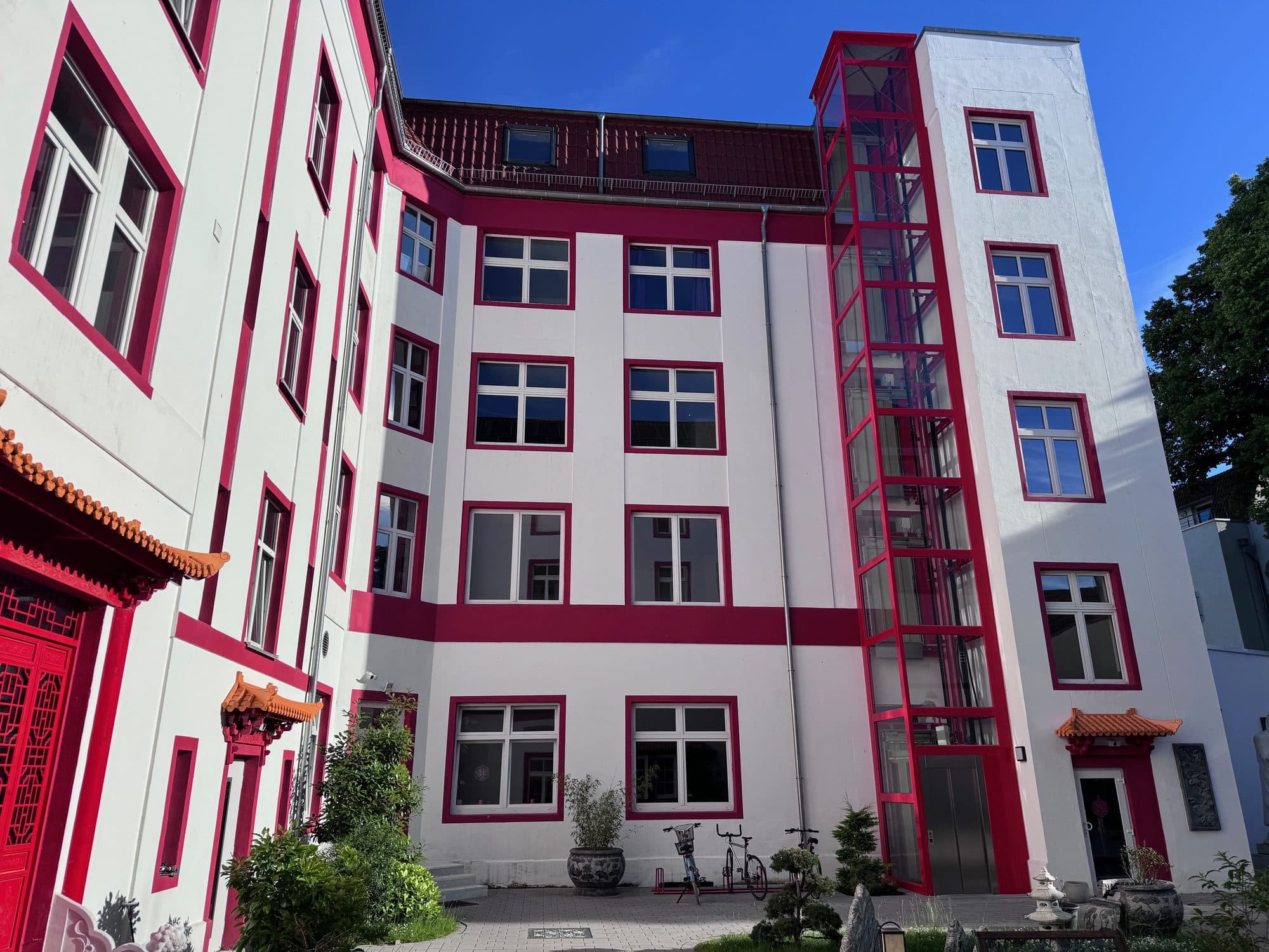 Rot-weiße Fassade des ChinaCenters mit geschwungenen Pagodendächern über den Eingängen