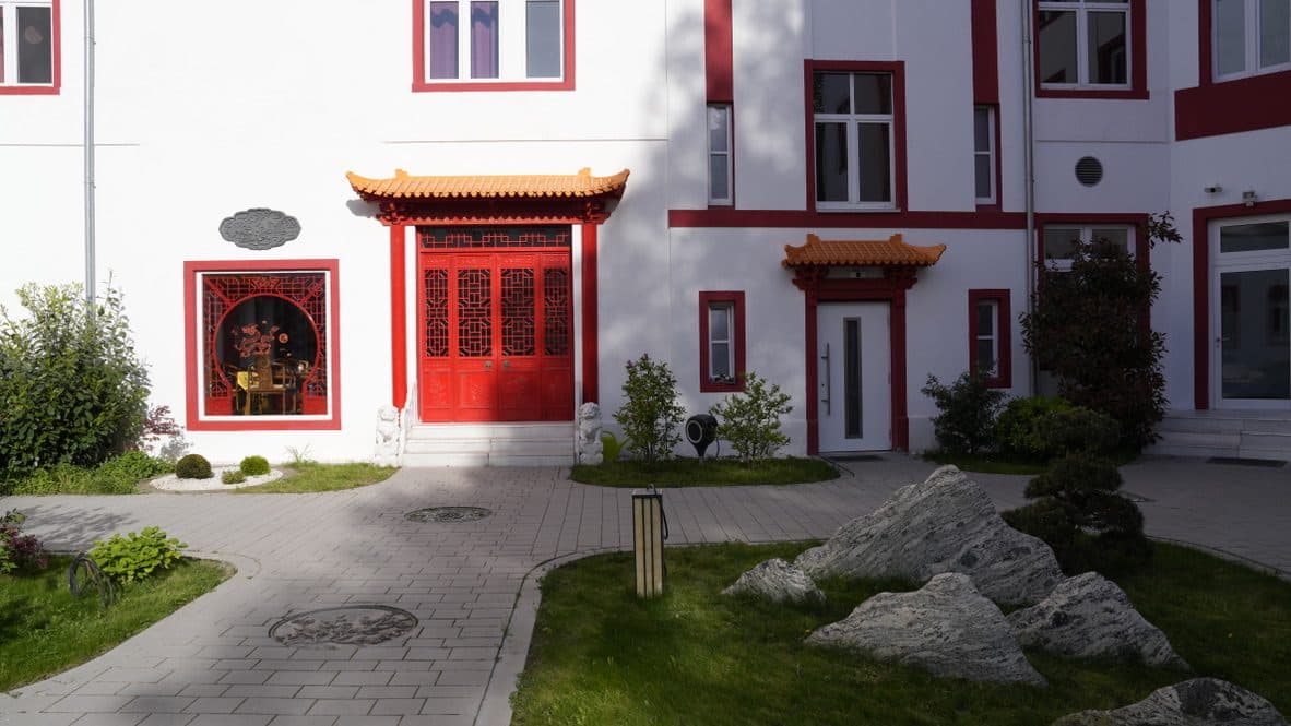 Rote Türen mit Pagodendächern, davor ein Steingarten mit Findlingen