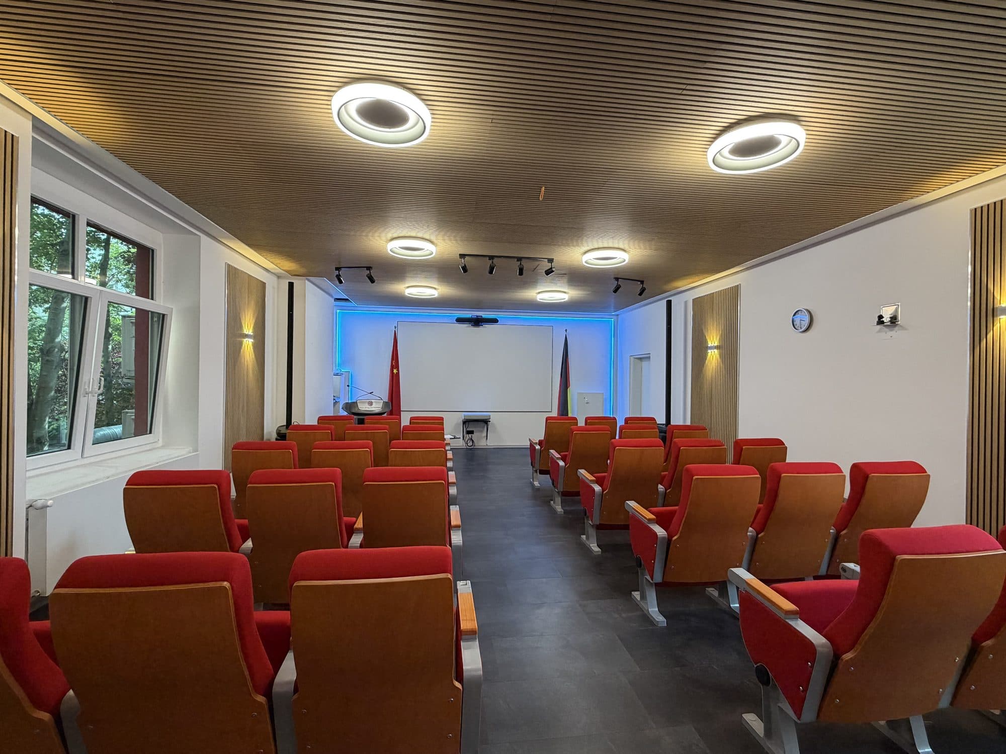 Hörsaal von hinten mit Blick auf Projektionsfläche und Rednerpult